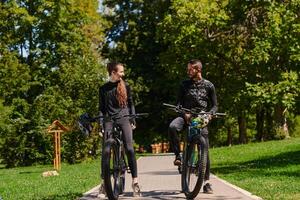 A sweet couple, equipped with bicycles and engrossed in coordinating their journey, checks their GPS mobile and watches while planning scenic routes in the park, seamlessly blending technology and photo