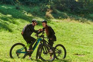 A sweet couple, equipped with bicycles and engrossed in coordinating their journey, checks their GPS mobile and watches while planning scenic routes in the park, seamlessly blending technology and photo