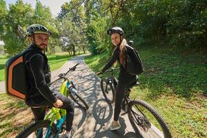 A sweet couple, adorned in cycling gear, rides their bicycles, their hands interlocked in a romantic embrace, capturing the essence of love, adventure, and joy on a sunlit path photo