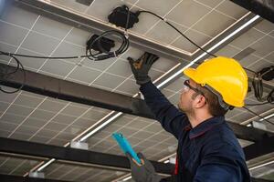 Engineer technical service checking solar panel while monitoring the system of solar panel on his tablet to make sure that's it work properly photo