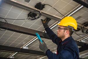 Engineer technical service checking solar panel while monitoring the system of solar panel on his tablet to make sure that's it work properly photo