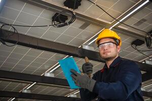 Engineer technical service checking solar panel while monitoring the system of solar panel on his tablet to make sure that's it work properly photo