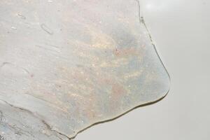 Close-Up of Pink and Gold Shimmer Gel Texture with Brush Strokes on White Background photo