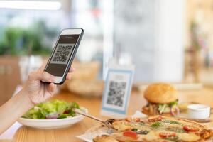 Woman use smartphone to scan QR code to pay in cafe restaurant with a digital payment without cash. Choose menu and order accumulate discount. E wallet, technology, pay online, credit card, bank app. photo