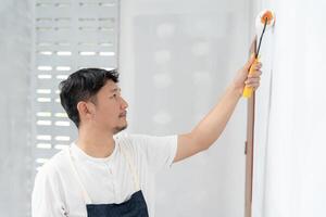 painter man, brush in hand for products to restore and paint the wall, indoor the building site of a house, wall during painting, renovation, painting, contractor, Architect, construction worker photo