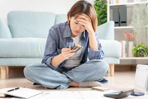 Stressed and headache asian woman with large bills or invoices no money to pay to expenses and credit card debt. shortage, Financial problems, mortgage, loan, bankruptcy, bankrupt, poor, empty wallet photo