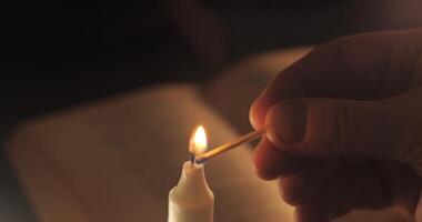 Lighting a candle. Old book on the table. Reading and teaching by candlelight at night. video