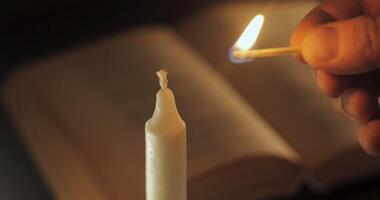 Lighting a candle. Old book on the table. Reading and teaching by candlelight at night. video