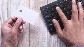A person holding a credit card next to a keyboard video