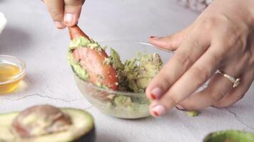 A person is using a spoon to spread avocado on a bowl video