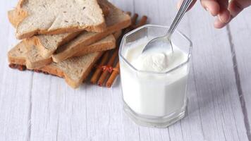 A glass of milk with a spoon and slices of bread video