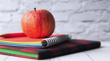 An apple sits on top of a stack of notebooks video