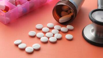 A stethoscope and a bottle of pills on a pink background video