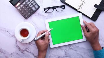 Green screen tablet with business person hands on table with cup of coffee and calculator video