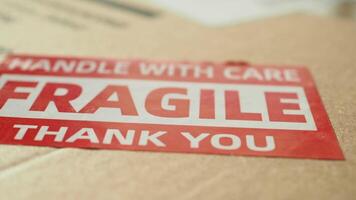 A cardboard box marked with a caution label for fragile goods handling during shipping video