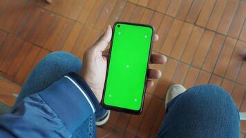 A smartphone featuring a green screen display is held in a persons hand for better visibility video