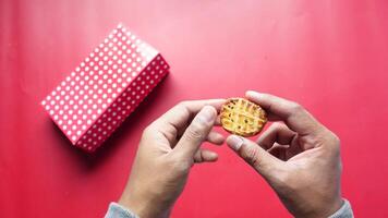 A Hand Grasping a Delicious Cookie in Close Proximity to a Vibrant Red Polka Dot Box video