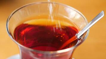A refreshing cup of brewed tea as sugar is being skillfully added for optimal flavor video