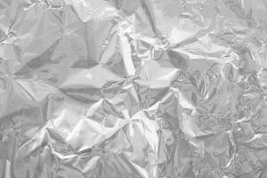 Close-up of Crumpled Silver Foil Wrapping Paper Texture with Wavy Metallic Surface photo