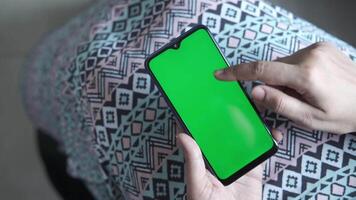 A man is using a smartphone with a green screen video
