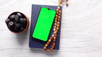 Green screen on smartphone with dates and rosary on white wooden table video