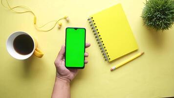 Green screen smartphone with a notebook and coffee on yellow background video