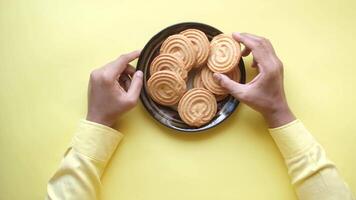 A person holding a plate of cookies on a yellow background video