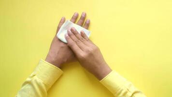 A person wiping their hands on a yellow background video