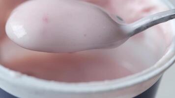 A spoonful of yogurt is being held up to the camera video