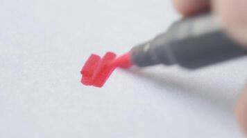 A person is using a red marker to write on a piece of paper video