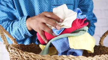 A man is holding a basket with several different colored towels video
