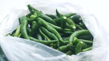 A bag of green peppers sitting on top of a white surface video