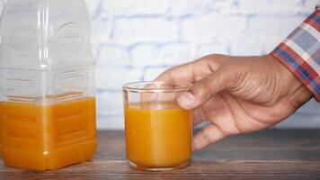 A man holding a glass of orange juice next to a bottle video