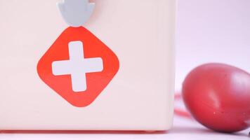 A red cross on a white background with a red stethoscope video