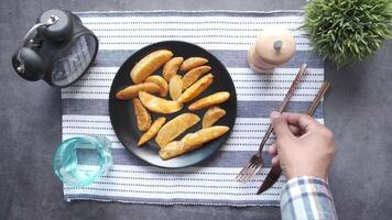 A person holding a fork and knife next to a plate of french fries video