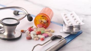 A stethoscope, pills and a clipboard on a table video