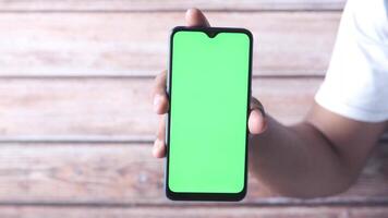 A man holding a smartphone with a green screen video
