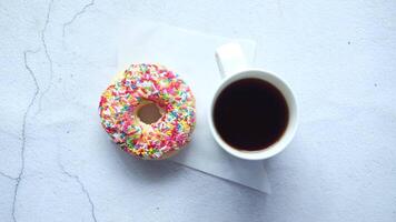 A cup of coffee and a donut on a white surface video