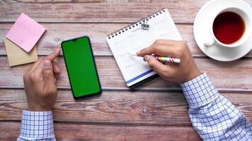 Man's hands writing on a notepad with a smartphone and a cup of coffee video
