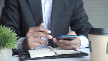 A man in a suit is using his phone while sitting at a table video