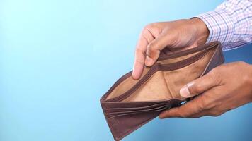 A man holding an empty wallet on a blue background video