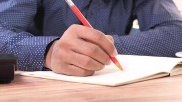 A man is writing on a notebook with a pencil video