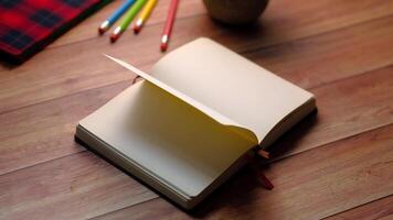 An open notebook with pencils and a red notebook on a wooden table video