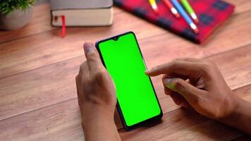 Man using smartphone with green screen on wooden table video
