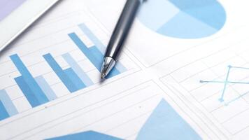 A pen and a tablet on a paper with graphs and charts video
