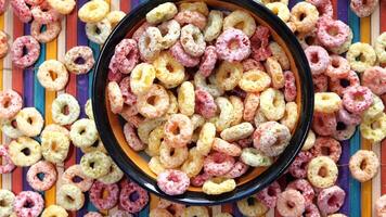 A bowl of colorful cereal rings on a colorful striped table video