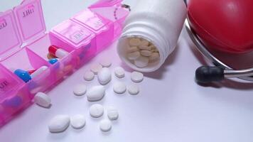 A pink pill box with pills and a stethoscope video