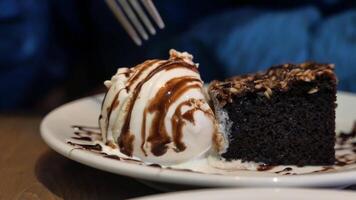 A piece of cake on a plate with ice cream and a fork video