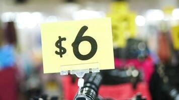 A yellow sign with a price of 6 is displayed in a store video