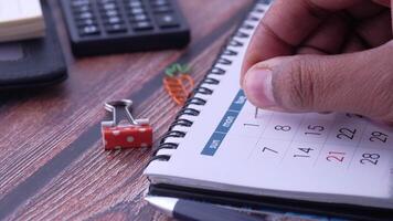 A man's hand writing on a calendar with dice and calculator video